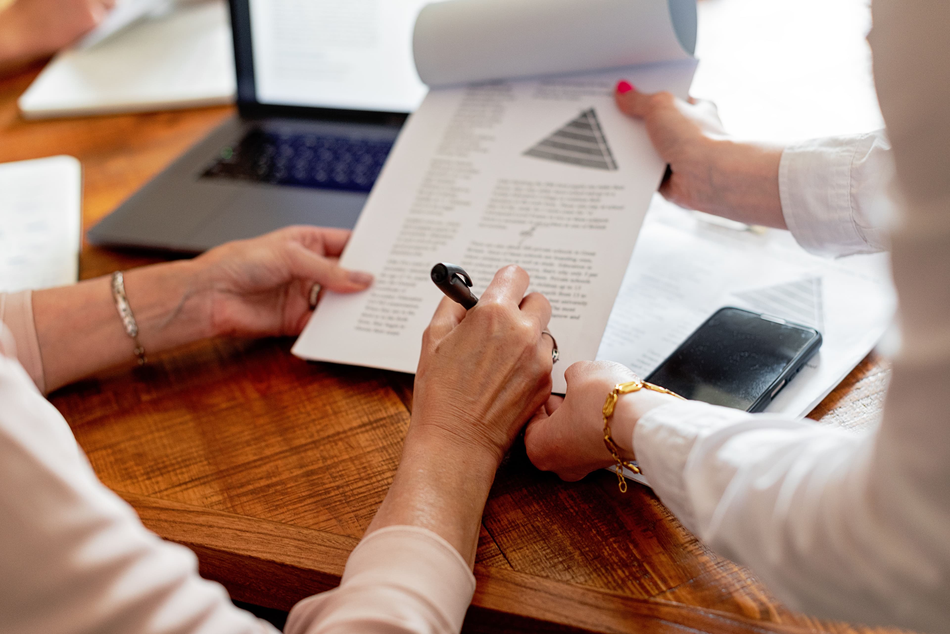 Deux femmes examinant des documents à une table, engageant une discussion de travail.